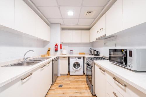 a kitchen with white cabinets and a sink and a dishwasher at RAKvista Beach Residence- Marjan Island in Ras al Khaimah