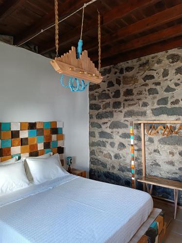 1 dormitorio con cama y pared de piedra en Avó da Rosa 3 en Povoação
