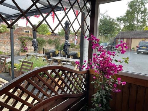a wooden bench on a porch with pink flowers at The Star Inn in Nafferton