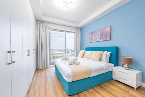 a blue bedroom with a bed and a window at RAKvista Beach Residence- Marjan Island in Ras al Khaimah