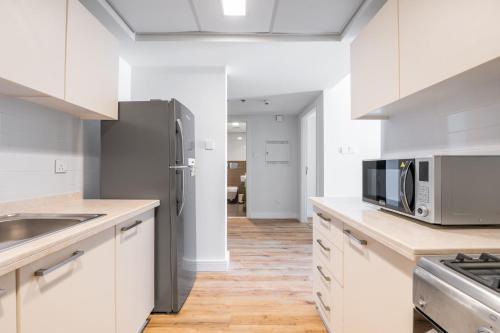 a kitchen with white cabinets and a stainless steel refrigerator at RAKvista Beach Residence- Marjan Island in Ras al Khaimah