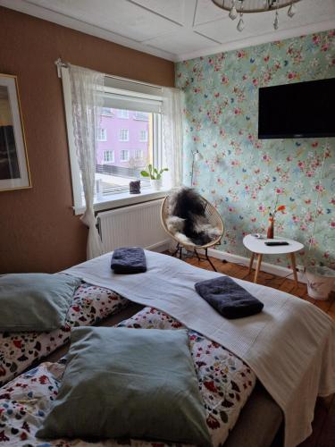 a bedroom with two beds and a window and a chair at Guesthouse Hugo in Sørvágur