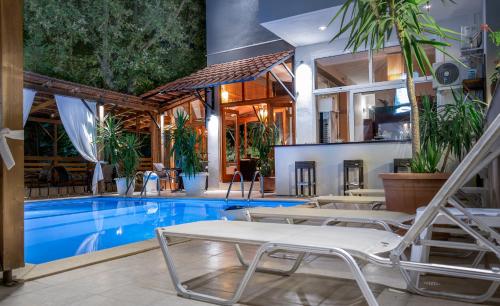 a pool with lounge chairs next to a house at Kipos Resort in Nea Peramos