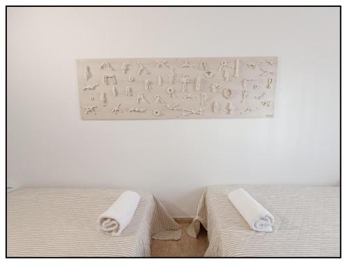 two beds in a white room with towels on them at APARTAMENTO CENTRICO JUNTO AL MAR - WIFI FREE in Salou