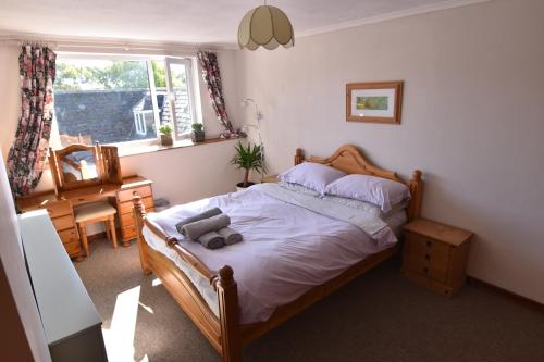 une chambre avec un lit avec un ours en peluche dessus dans l'établissement Spacious cottage in the village of Wembury, à Wembury