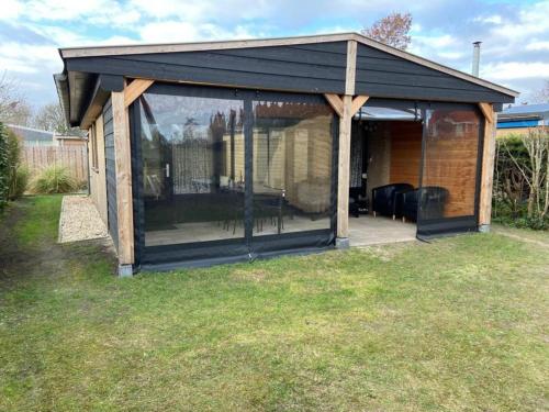 a screened in house with a black roof at Horrelshoogte 15, cozy house with private garden near the beach - not for companies in Ouddorp
