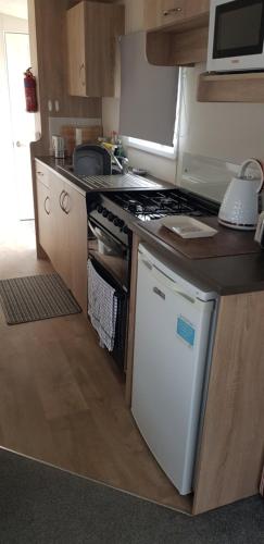 a small kitchen with a stove and a dishwasher at Chainbridge in Selsey
