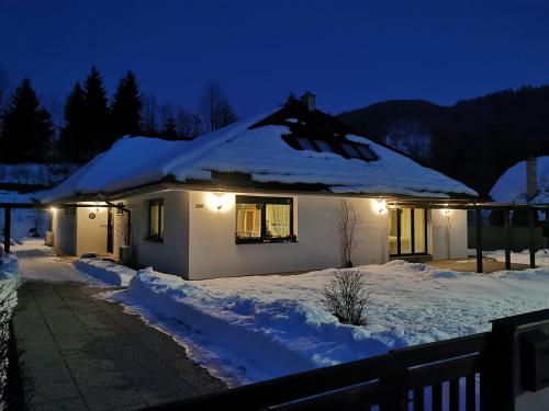a house with snow on the roof at night at Bystra 150 in Bystrá