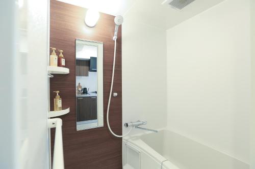 a bathroom with a shower with a sink and a mirror at LEOPARD Shinsaibashi in Osaka