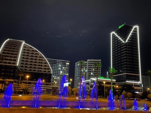 a city at night with a fountain and buildings at Prestigio apart Batumi in Batumi