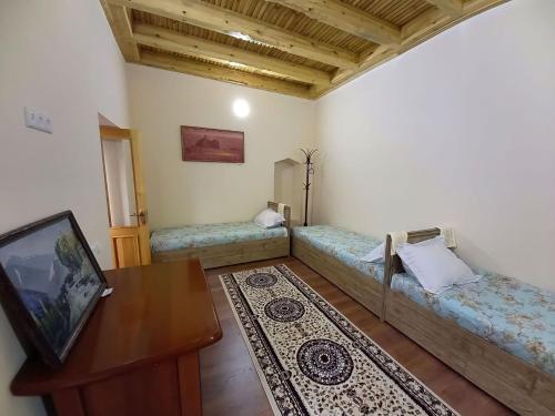 uma sala de estar com duas camas e uma mesa em Rassom Hostel em Samarkand