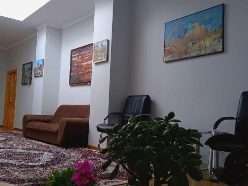 uma sala de estar com um sofá e cadeiras e uma planta em Rassom Hostel em Samarkand