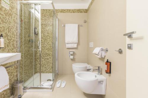 a bathroom with a shower and a toilet and a sink at Hotel Catalunya in Alghero