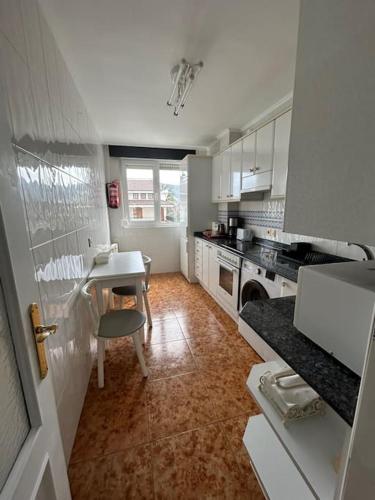 a small kitchen with a table and a table and a stove at Playa de Berria -Apartamento con piscina y vistas al mar in Santoña