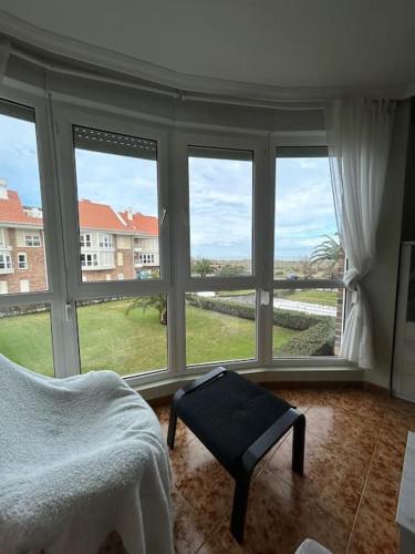 a bedroom with large windows and a bed and a table at Playa de Berria -Apartamento con piscina y vistas al mar in Santoña