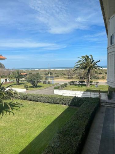 a building with a walkway next to a field of grass at Playa de Berria -Apartamento con piscina y vistas al mar in Santoña