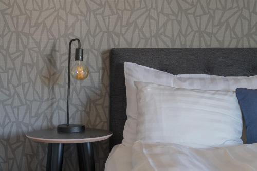 a lamp on a night stand next to a bed at Aurum Hotel in Skellefteå