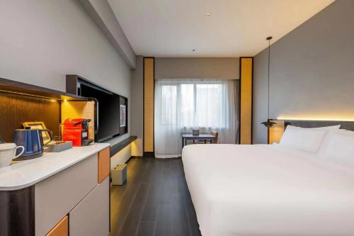 una camera d'albergo con un grande letto e una TV di UrCove by HYATT Shanghai Jinqiao Centre a Shanghai