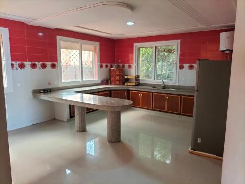 a large kitchen with red walls and a large stone table at saidia center in Saïdia