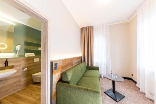 a bathroom with a green couch and a sink at Hotel Waldmühle in Zella-Mehlis