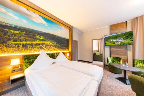 una habitación de hotel con una cama y una gran pintura en la pared en Hotel Waldmühle, en Zella-Mehlis
