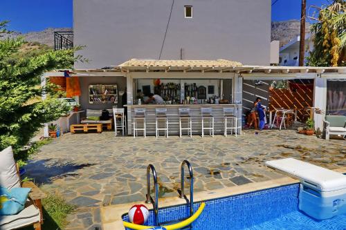 a swimming pool next to a house with a bar at Calma Apartments & Studios in Plakias