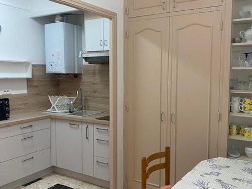 une petite cuisine avec des armoires blanches et une table dans l'établissement Studio cosy avec terrasse, parking et wifi - Idéal cures et centre-ville, Amélie-les-Bains - FR-1-703-3, à Amélie-les-Bains-Palalda