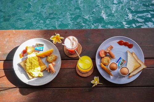 twee borden eten op een tafel naast een zwembad bij Pera ONE Villas in Gili Trawangan