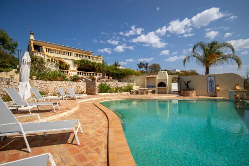 a swimming pool with chairs and a building at Casa Sapo Gordo in Luz