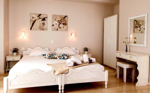 a white bedroom with a white bed and a mirror at Calma Apartments & Studios in Plakias