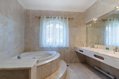 a bathroom with a tub and two sinks and a mirror at Casa Sapo Gordo in Luz