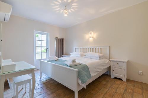 a bedroom with a white bed with a desk and a table at Casa Sapo Gordo in Luz