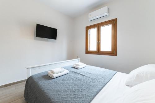 een witte slaapkamer met een bed en een raam bij Knossos House in Heraklion