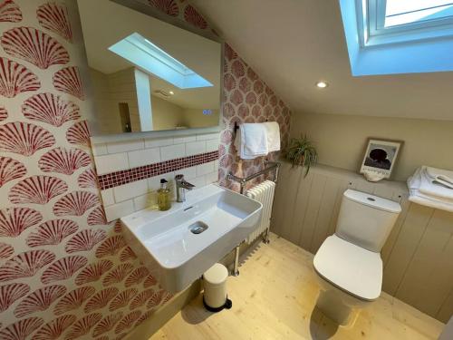 a bathroom with a sink and a toilet and a mirror at Mustard Pot Cottage in Eye