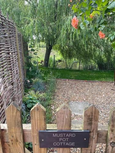 a wooden fence with a sign in a garden at Mustard Pot Cottage in Eye