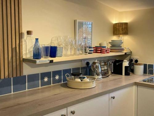 a kitchen with a counter with glasses on a shelf at Mustard Pot Cottage in Eye