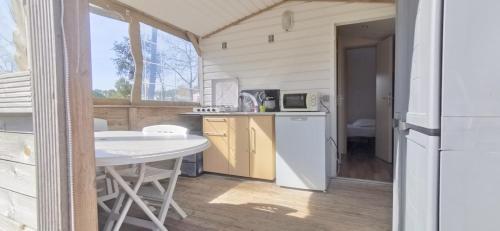 een keuken met een tafel en een witte koelkast bij locationestivale40 Bungalow petit budget océan forêt in Bias