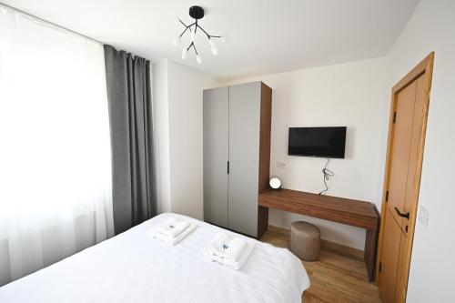 um quarto com uma cama e uma televisão na parede em Tasa Apartmani em Zlatibor