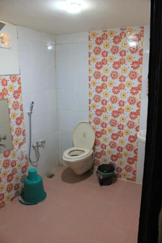a bathroom with a toilet and flowers on the wall at Avadale Tadoba - Stag Groups Not Allowed in Mohurli