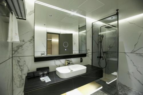 y baño con lavabo, espejo y ducha. en SH Amber City Stay en Jeju