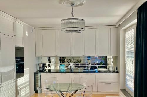 a kitchen with white cabinets and a glass table at Apartament Szafarnia DeLux in Gdańsk