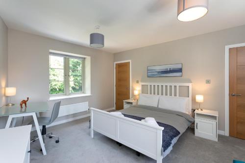 a bedroom with a white bed and a desk and a desk at Beautiful Honeycomb Cottage in heart of Cotswolds in Chipping Norton