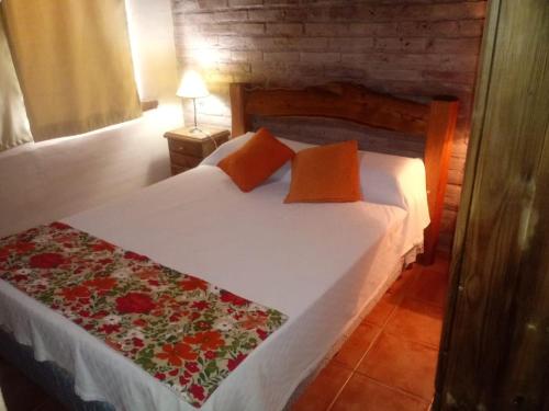 1 dormitorio con cama blanca y almohadas de color naranja en Cabañas El Refugio del Atuel en San Rafael