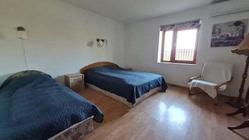 een slaapkamer met 2 bedden, een stoel en een raam bij Sarudi vendégház in Sarud