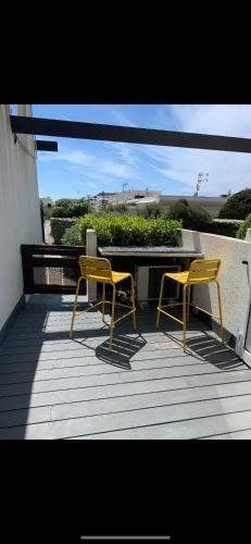 deux chaises jaunes et une table sur une terrasse dans l'établissement Studio port nature 2, au Cap d'Agde