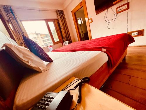 a bedroom with a bed with a phone on it at WooibHotels The Solitaire in Manāli