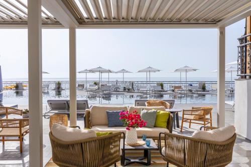 a patio with a couch and chairs and tables at Delta Hotels by Marriott Giardini Naxos in Giardini Naxos