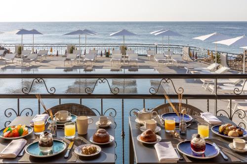 a table with plates of food on a balcony with the beach at Delta Hotels by Marriott Giardini Naxos in Giardini Naxos
