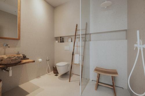 a bathroom with a toilet and a wooden stool at Amethyst Selene Paleros Couple's Hideaway in Paleros