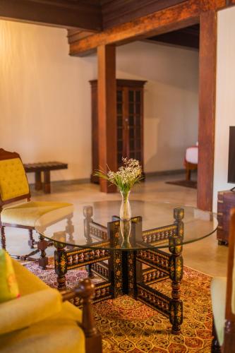 a living room with a glass table with a vase of flowers at Sawantwadi Palace Boutique Art Hotel in Sawantwadi